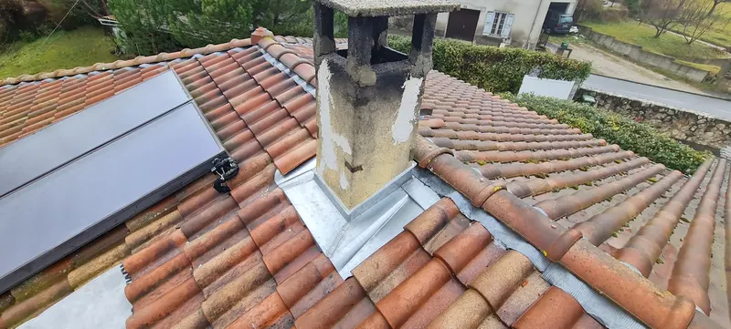 Couverture en tuiles autour d’une fenêtre de toit et d’une cheminée